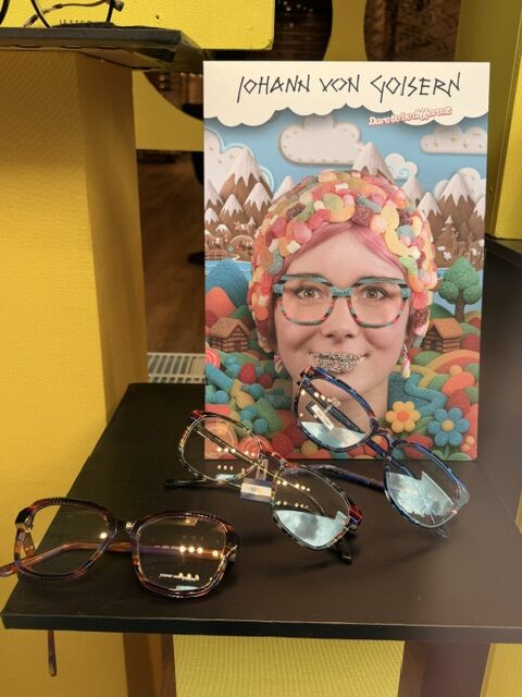 Brillenkollektion 'Johann von Goisern' im Schaufenster von Meller Optic mit bunter Werbetafel